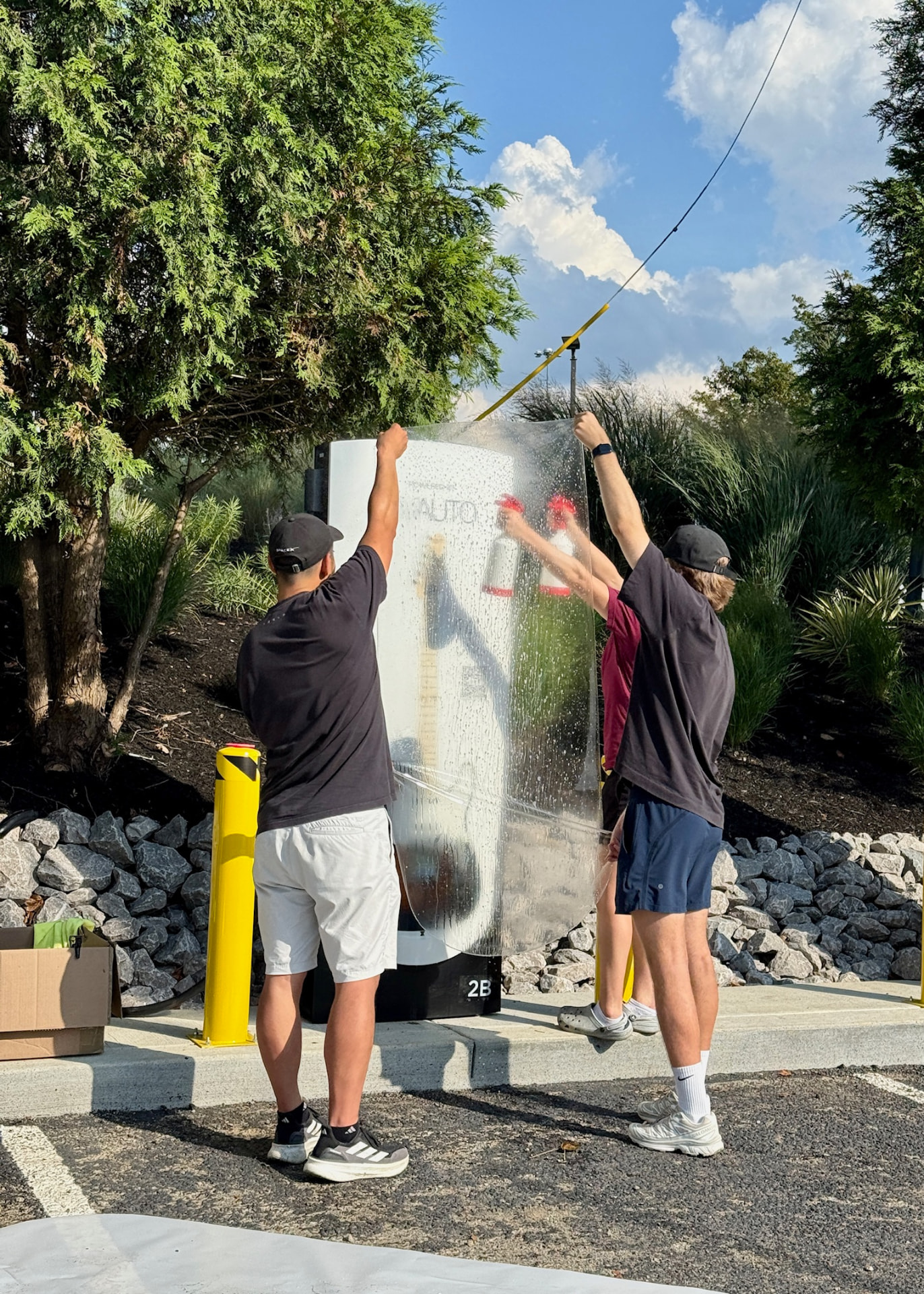 DIY Wrap Club install crew applying a printed vinyl wrap to a Supercharger post on site