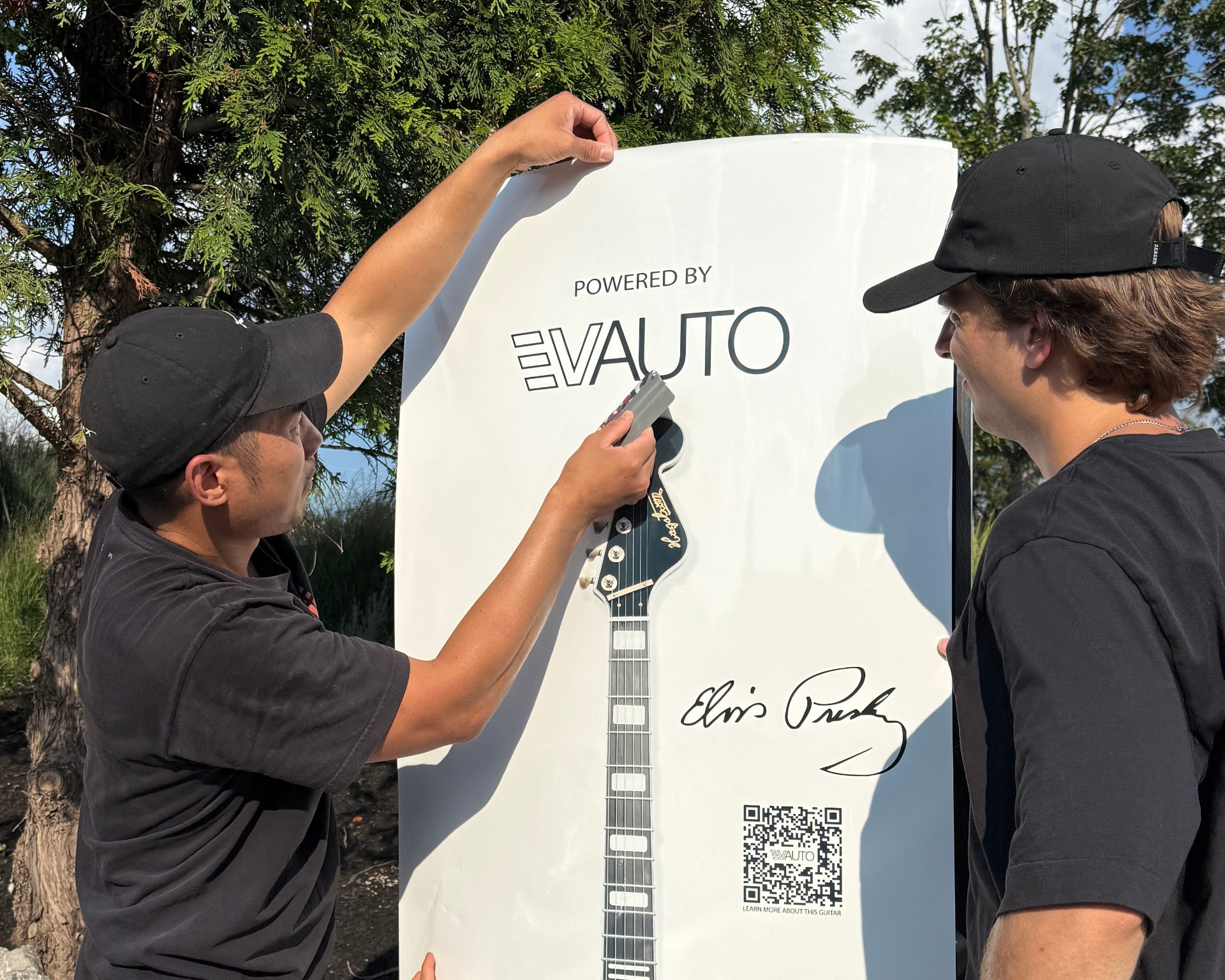 Installer applying a Powered by EVAUTO guitar graphic wrap to a Tesla Supercharger in Nashville, Tennessee